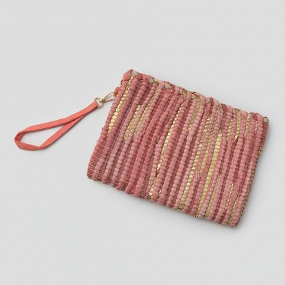 A woven clutch purse in dusty pink and gold with a coral pink wrist strap, shown on a light gray background.